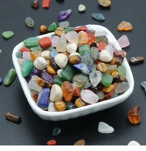 Polished natural crystal stones and colorful mineral gravel in a white ceramic bowl