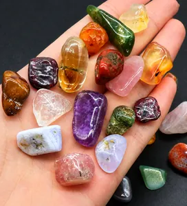Detailed close-up of mixed natural tumbled crystal stones held in hand on black background