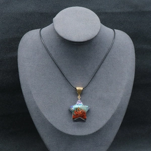Star-shaped resin pendant necklace with seven chakra gemstones on black jewelry bust