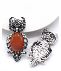 Détail de la broche hibou avec pierre orange et finition argentée de style vintage