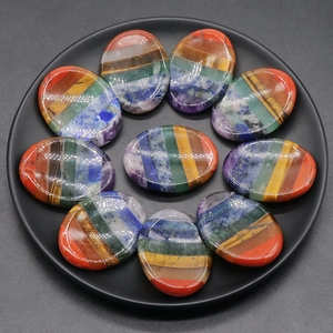 Set of 10 chakra worry stones with seven colorful natural crystals on a black tray