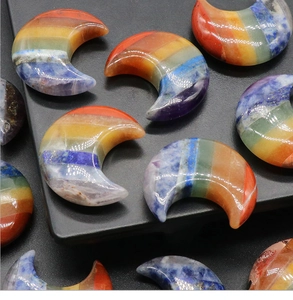 Polished colorful natural crystal crescent moon chakra stones stacked on black display stand
