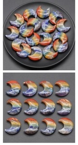 Polished moon-shaped seven chakra stones arranged in a grid and on a black tray