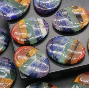 Close-up of polished oval chakra worry stones featuring layered natural healing crystals