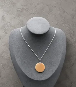 Detalle del colgante redondo de ágata naranja en busto de terciopelo gris con cadena plateada