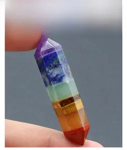 Macro detail of hand-held double-pointed hexagonal 7 chakra healing crystal stone column