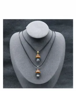 Détail macro de pendentifs champignons en pierre naturelle avec oeil de tigre et cordon noir
