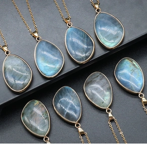 Détail macro de pendentifs en labradorite poire avec reflets bleus et bordure dorée