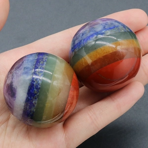 Pair of polished 7 chakra natural stone spheres held in hand for meditation and healing