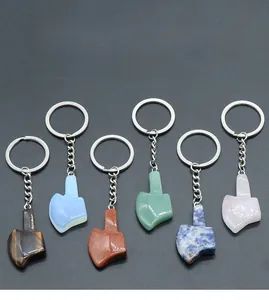 Flat lay of multiple axe-shaped natural stone keychains in tiger eye and quartz materials