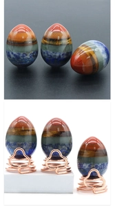 Polished chakra energy stone egg with layered colorful crystals on a rose gold stand