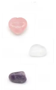 Detailed comparison of polished rose quartz heart, clear quartz oval, and raw amethyst stones