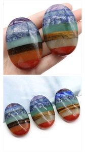 Detailed macro view of seven chakra balancing stones stacked in polished oval palm stone shape