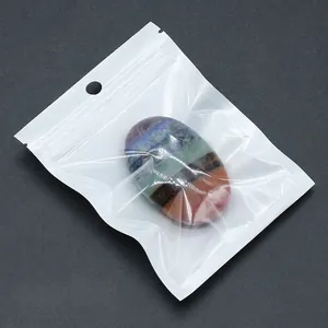 Oval chakra stone with colorful layers in a clear OPP bag on dark grey background