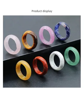 Close-up of assorted natural crystal rings including rose quartz and tiger eye on a black stand