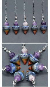 Macro detail of seven chakra natural stone pendulum with amethyst ball and silver chain