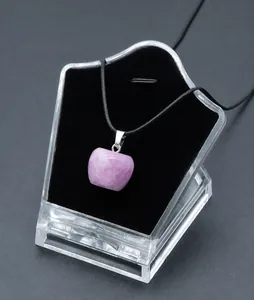 Macro detail of a 20mm pink crystal apple pendant with black cord on a velvet display