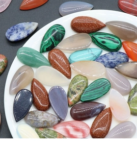 Colorful teardrop waterdrop shaped natural crystal gemstones in a white ceramic dish