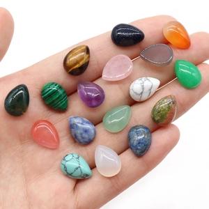 Polished teardrop natural crystal stones and colorful quartz cabochons in hand