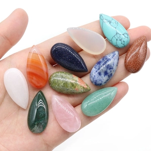 Hand holding assorted teardrop natural crystal gemstones for DIY jewelry settings