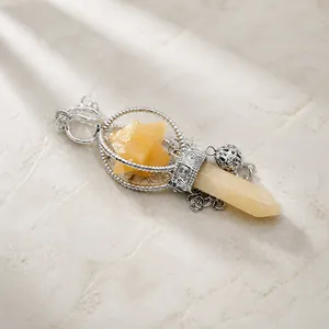 Detail of yellow hexagonal crystal pendant with silver ornate clasp in packaging