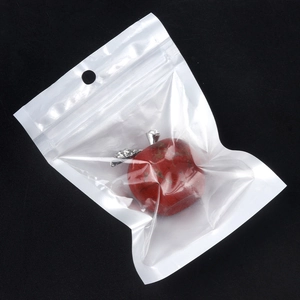 Apple-shaped natural red crystal stone ornament with silver leaf detail on black background