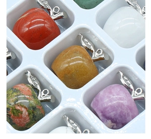Close-up of mini apple-shaped natural stone pendants in a white grid display box