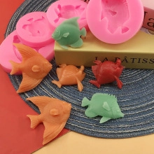 Detail of pink silicone molds and finished fish-shaped crafts for ocean themed cake decor