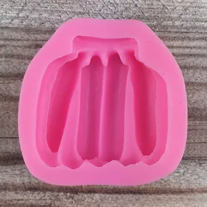 Pink silicone mold with a skirt shape for fondant and DIY crafts on a wooden surface