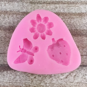 Macro detail of pink silicone mold with flower, butterfly, and strawberry cavities