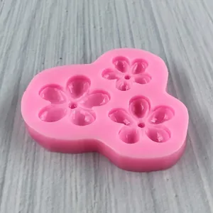 Pink silicone mold featuring three five-petal flower cavities for cake decorating