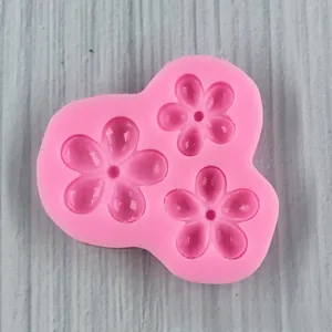 Detailed macro view of a 3-cavity pink silicone flower mold for fondant and baking