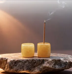 Macro detail of square yellow jade incense holder on raw stone tray with smoke