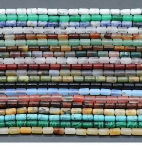 Various 6x10mm cylinder crystal agate stone beads arranged on dark textured surface