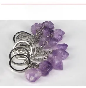 Close-up of raw amethyst crystal keychains with silver metal rings on white background