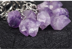 Detailed macro view of natural raw amethyst crystal cluster keychain on black mesh base
