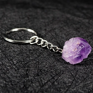 Natural amethyst raw stone keychain with silver metal ring on a textured dark surface