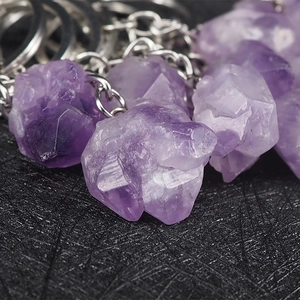 Natural amethyst crystal raw stone keychain with silver metal ring on a textured base