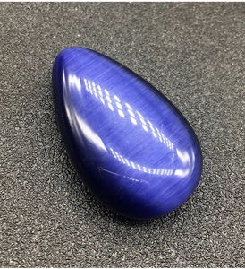 Vista macro di una pietra a goccia blu scuro con effetto occhio di gatto su nero