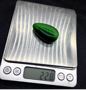 Dettaglio pietra a goccia verde scuro da 22,8g con effetto occhio di gatto su una bilancia