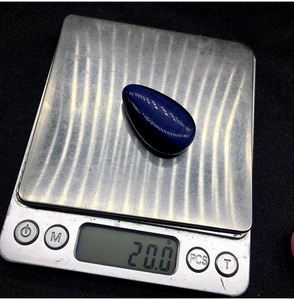 Macro di un ciondolo a goccia in pietra occhio di gatto blu da 20g su bilancia