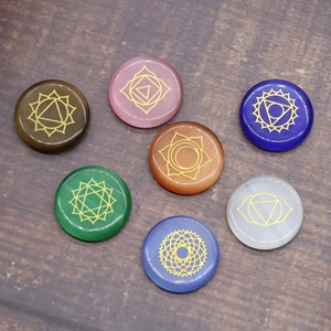Set of 7 colorful polished chakra healing stones with golden yoga symbols on wood