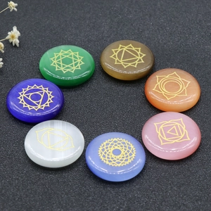 Polished opal chakra stones set with golden yoga symbols on textured background