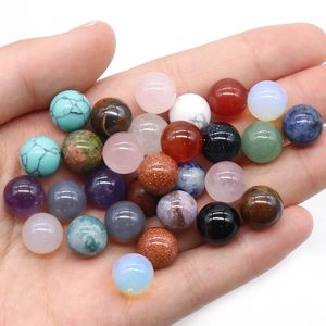 Mélange de perles en pierres précieuses polies de 10 mm tenues dans la main