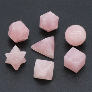 Seven-piece natural rose quartz geometric set for yoga and meditation on a dark background