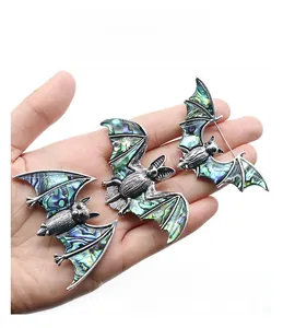 Gros plan détaillé de broches chauve-souris avec ailes en nacre d'abalone tenues à la main