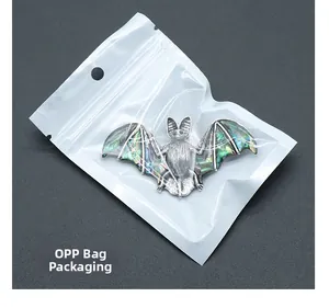 Détail d'un pendentif chauve-souris en nacre d'abalone dans son sachet plastique OPP