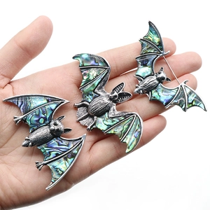 Trois broches chauve-souris en argent vieilli avec nacre d'abalone présentées sur une main