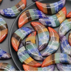 Macro shot of colorful seven chakra moon-shaped gemstone pendants with natural textures