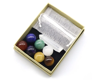 Detailed set of 7 colorful chakra crystal spheres with a clear quartz wand in a gift box